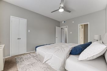 A bedroom with a bed, pillows, and a ceiling fan.